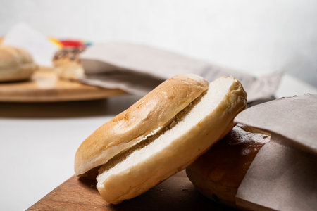 Closeup view of slice of bagel breads from brown paper bag on wooden board on a white background