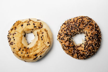 Closeup view of slice of bagel breads with sesame seeds isolated over white background. Top and bottom part. Top viewの写真素材
