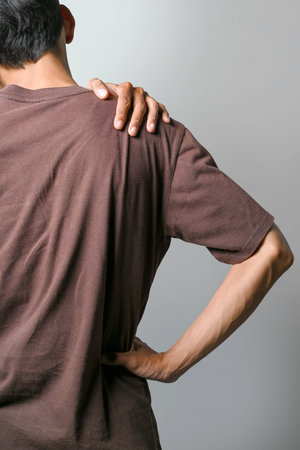 Portrait of a man suffering shoulder pain isolated over a white background. Concept of healthcareの写真素材