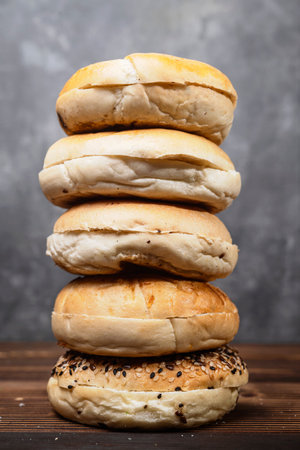 Closeup view of a pile of a collection of bagel breads with various kinds on a wooden boardの写真素材