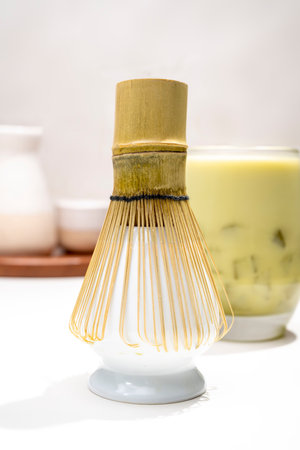 Closeup view of iced matcha green tea on the glass with a traditional bamboo brush whisk or chasen on the table. Accessories for making matcha green teaの写真素材