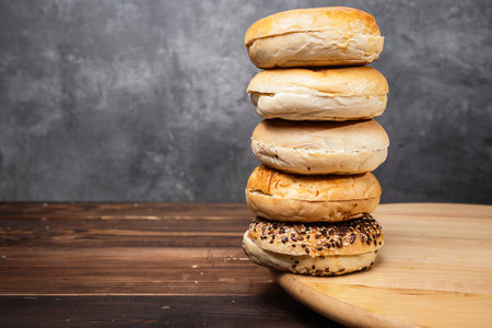 Closeup view of a pile of a collection of bagel breads with various kinds on a wooden boardの写真素材