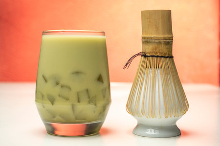 Closeup view of iced matcha green tea on the glass with a traditional bamboo brush whisk or chasen on the table. Accessories for making matcha green teaの写真素材