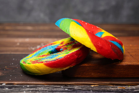 Closeup view of a slice of a rainbow bagel bread on a wooden boardの写真素材