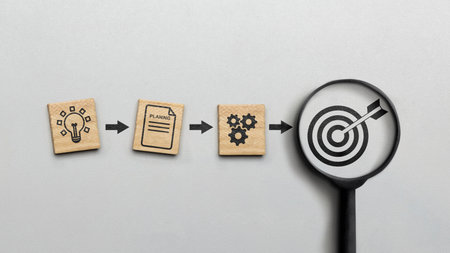 Magnifying glass showing a dart and an arrow icon on a white background. Concept of the action planの写真素材