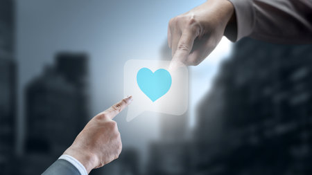 Two business hands touching an icon of a heart on a speech bubble. Technology innovation on the virtual screen. Concept of social mediaの写真素材