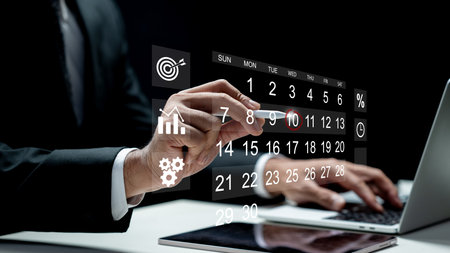 Businessman using a laptop while marking the date on a virtual calendar on a tablet screen. Technology innovation on a virtual screen. Concept of schedule or time managementの写真素材