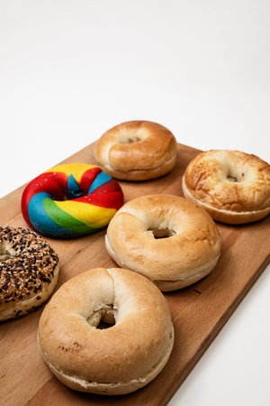 Closeup view of a collection of bagel breads with various kinds on a wooden board isolated over a white backgroundの写真素材