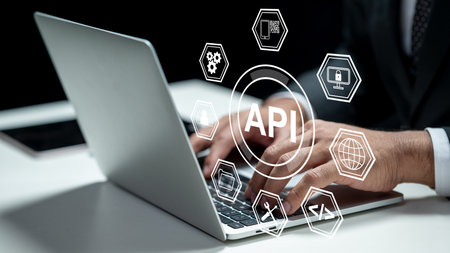 Businessman using a laptop while showing an icon of API. Tablet on the table. Technology innovation on a virtual screen. Concept of Application Programming Interfaceの写真素材