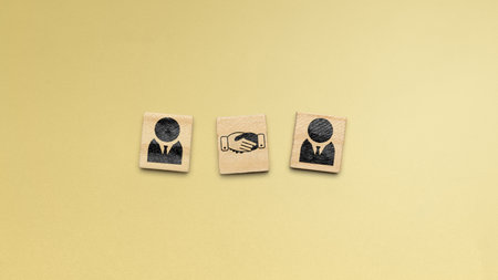 Wooden cubes with a handshake icon between people icon on wooden cubes in a colored background. Concept of negotiationの写真素材