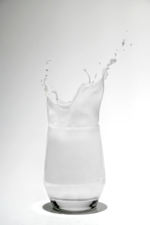 Milk in a glass with a splash on a white backgroundの写真素材