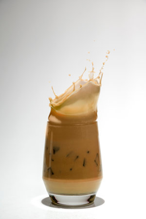 Iced caramel with ice cubes in a glass with a splash on a white backgroundの写真素材