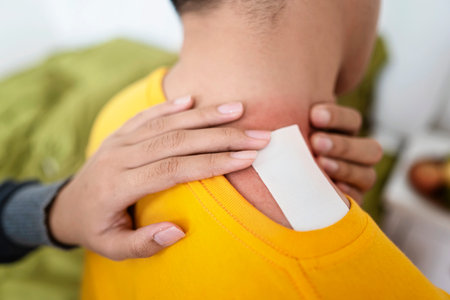 Woman applies a neck pain patch to her husband neck in the bedroom. Self-care and wellness routines...