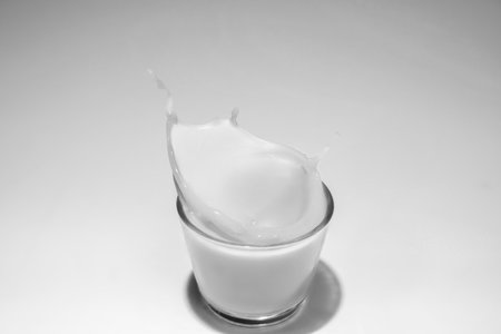 Milk in a glass with a splash on a white backgroundの写真素材