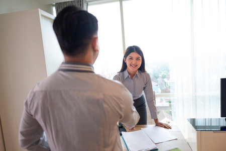 Indonesian southeast asian business people with paperwork meeting and handshake after reaching an agreement in teamwork for partnership or collaboration. Team collaboration and meetings conceptの写真素材