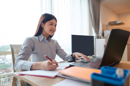 Indonesian southeast asian businesswoman working with paperwork and a laptop on the table inside the...