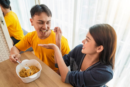 Indonesian southeast asian couple family eating noodles meal together in the dining roomの写真素材