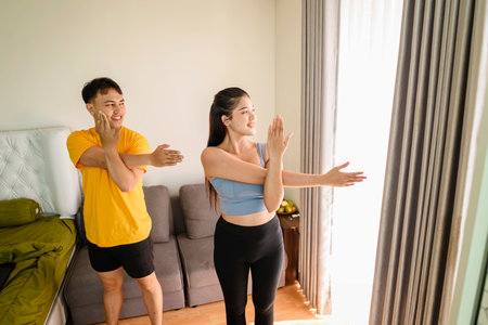 Indonesian southeast asian couple stretching before a workout at home for a healthy lifestyle and body care. Fitness and active lifestyles conceptの写真素材