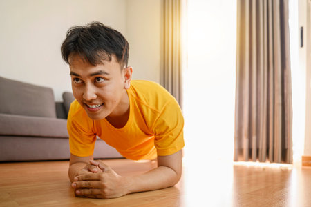 Indonesian southeast asian man stretching his leg before a workout at home for a healthy lifestyle and body care. Fitness and active lifestyles conceptの写真素材