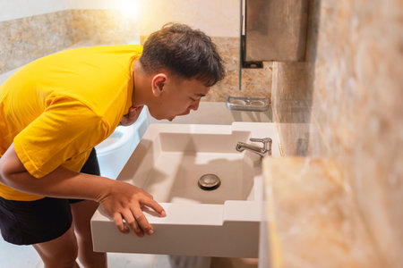 Indonesian southeast asian man wants to vomit, feeling sick and unwell, ate too much unhealthy junk food or food poisoning. Healthcare conceptの写真素材