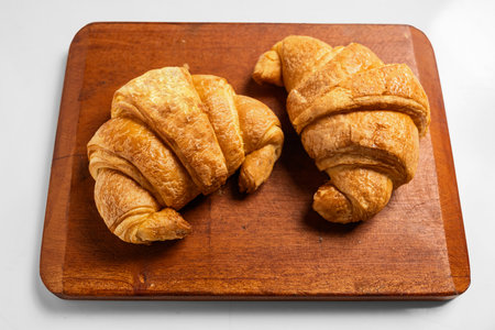 Freshly baked croissants on a wooden tray isolated over a white backgroundの写真素材