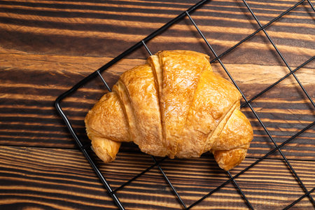 Freshly baked croissant on a cooling tray with a wooden background. Top viewの写真素材