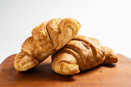 Freshly baked croissants on a wooden tray isolated over a white backgroundの写真素材