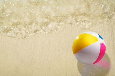 Aerial view of colorful beach ball on a beautiful sandy beach under clean and transparent blue ocean...