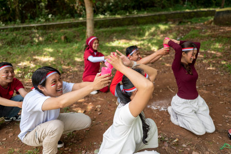 Portrait of an Indonesian southeast asian people celebrate Indonesia Independence Day on the 17th of August with a game of moving flour with plastic glasses outdoors. Concept of Kemerdekaan Indonesiaの写真素材