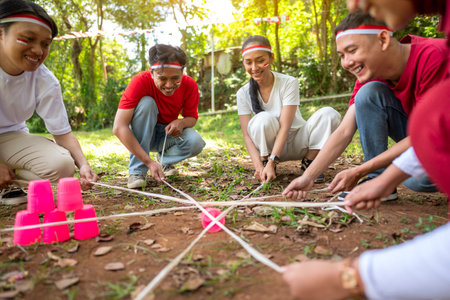 Portrait of an Indonesian southeast asian people celebrate Indonesia Independence Day on the 17th of August with a game of building a plastic glass stack with a stick outdoors. Concept of Kemerdekaan Indonesiaの写真素材