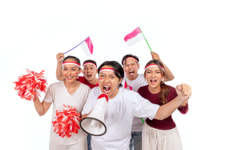 Indonesian southeast asian people celebrate Indonesia Independence Day on 17th of August by holding megaphone and Indonesian national flag isolated white background. Concept of Kemerdekaan Indonesiaの写真素材