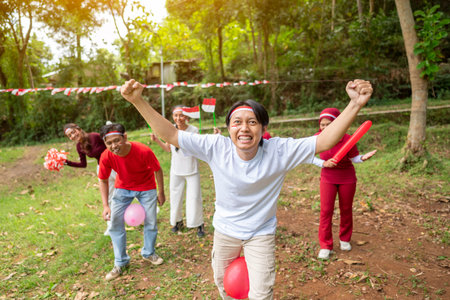 Portrait of an Indonesian southeast asian people celebrate Indonesia Independence Day on the 17th of August with a game of keep the balloon from blowing out outdoors. Concept of Kemerdekaan Indonesiaの写真素材