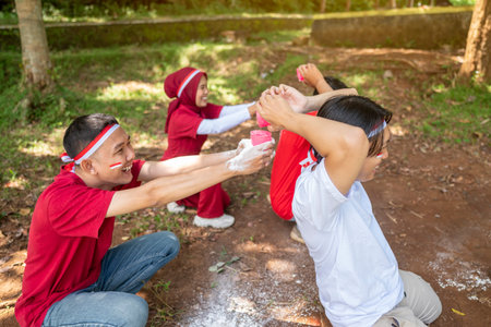 Portrait of an Indonesian southeast asian people celebrate Indonesia Independence Day on the 17th of August with a game of moving flour with plastic glasses outdoors. Concept of Kemerdekaan Indonesiaの写真素材