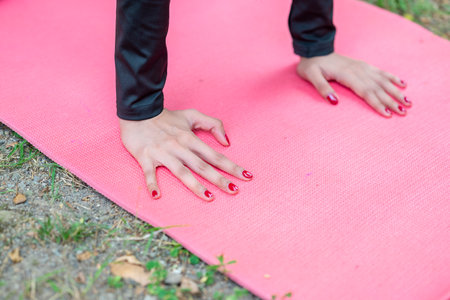 Woman in a sporty outfit practices exercise on a mat in a public park outdoors. Concept of a Healthy active lifestyleの写真素材