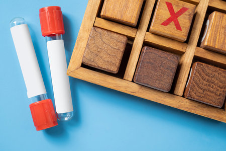 Closeup view of an empty test tube with a wooden tic tac toe game on a blue background. Mockup or Copy space. Concept of healthcare and medicineの写真素材