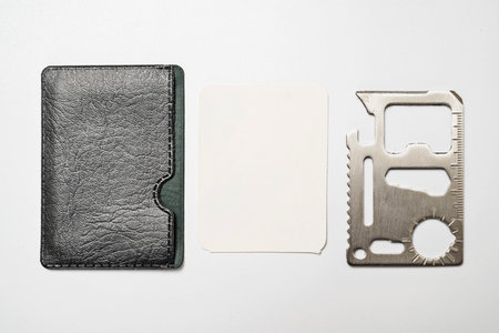 Minimalist leather wallet with blank card and stainless steel multi tool isolated over a white background. Mockup or Copy spaceの写真素材