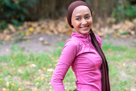 Indonesian southeast asian muslim woman in a sporty outfit practices yoga in a public park outdoors. Concept of a Healthy active lifestyleの写真素材