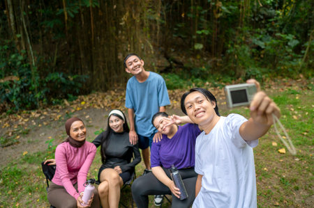 Indonesian southeast asian people in a sporty outfit taking a selfie with a camera together after practice exercise in a public park outdoors. Concept of a Healthy active lifestyleの写真素材