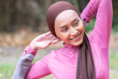 Indonesian southeast asian muslim woman in a sporty outfit practices yoga in a public park outdoors. Concept of a Healthy active lifestyleの写真素材