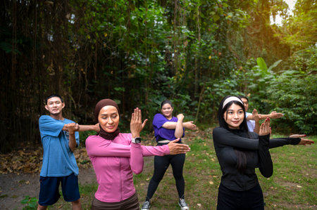 Indonesian southeast asian people in a sporty outfit practice exercise together in a public park outdoors. Concept of a Healthy active lifestyleの写真素材