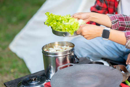 People are preparing for outdoor meal, showcasing a portable stove and various ingredients. The scene of the lifestyle of enjoying food in a natural settingの写真素材