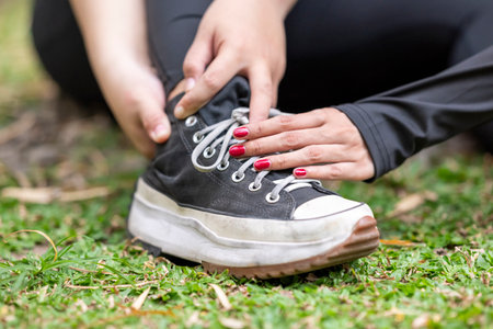 People in a sporty outfit feeling sore on foot after practice exercise in a public park outdoors. Concept of a Healthy active lifestyleの写真素材