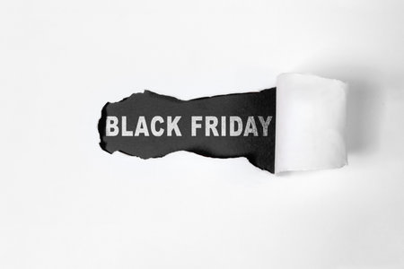 Top view of white ripped paper and text of Black Friday on a black background. Copy space. Flat lay. Black Friday sale conceptの写真素材