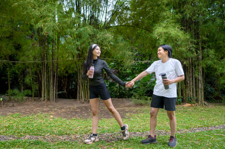 Indonesian southeast asian couple in a sporty outfit resting together after a practice exercise in a public park outdoors. Concept of a Healthy active lifestyleの写真素材