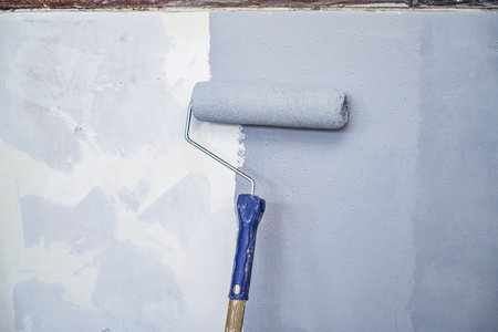 Construction worker using a paint roller to apply paint to a wall during home renovation. Home renovation projectの写真素材