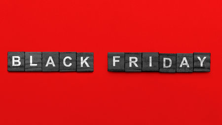 Closeup view of Black Friday on a black wooden cube with a red background. Copy space. Black Friday sale conceptの写真素材