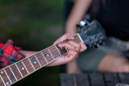 Man playing an acoustic guitar outdoors. Showing a relaxed and enjoyable lifestyle. The scene of the lifestyle of enjoying camping in a natural settingの写真素材