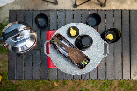 Top view of portable camping table is set up outdoors with a cooking stove and a pot. A scene of outdoor camping and cookingの写真素材
