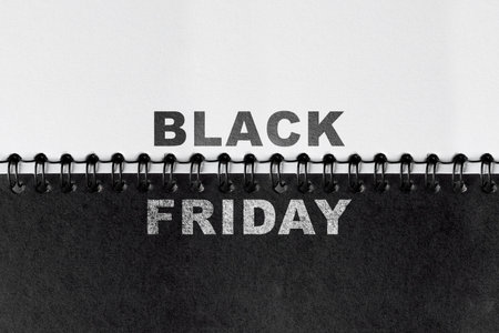 Top view of the text of Black Friday on a white and black paper background. Copy space. Flat lay. Black Friday sale conceptの写真素材