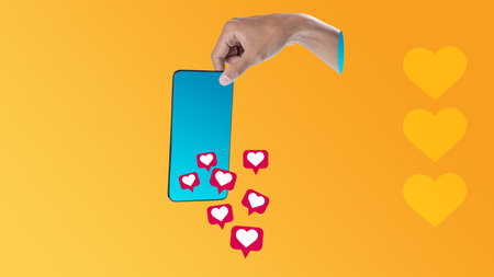 Human hand holding a cellphone with like symbols of social media icons with a colored background. Mockup, Copy space, or Template. Collage art of Social Mediaの写真素材